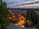 Elegant home with warm exterior lighting, a covered front entry, and beautiful landscaping at dusk at 4030 E Forbes Ct, Greenwood Village, CO 80121
