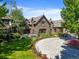 An elegant estate with a brick facade, lush lawns, colorful landscaping, and a circular driveway at 4030 E Forbes Ct, Greenwood Village, CO 80121
