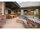 Covered outdoor living area with a dining table, grill, and fireplace, perfect for entertaining at 4030 E Forbes Ct, Greenwood Village, CO 80121