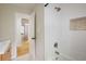 Bathroom featuring a tiled shower with built-in shelf and a view to the hallway with wood flooring at 4470 W Lakeridge Rd, Denver, CO 80219