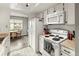 Galley kitchen with white appliances and cabinets opening to the dining area at 540 S Forest St # 6-203, Denver, CO 80246