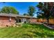 Spacious backyard featuring a brick house, lush grass, artificial turf, and mature trees at 6572 E Dakota Ave, Denver, CO 80224