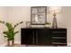 Modern sideboard with greenery, decor, and textured black drawers stands beside a tall lamp at 6572 E Dakota Ave, Denver, CO 80224