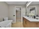Bright bathroom featuring a double vanity, soaking tub, modern fixtures and wood look flooring at 1596 S Stuart St, Denver, CO 80219