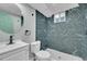 Updated bathroom with modern vanity, round mirror, and blue marble-look tiled shower at 1596 S Stuart St, Denver, CO 80219