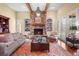 Cozy living room featuring a stone fireplace, beamed ceilings, and built-in bookshelves at 1 Gooseberry Ln, Cherry Hills Village, CO 80113