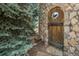 Stone gate with decorative wooden door surrounded by lush greenery and mature trees at 1 Gooseberry Ln, Cherry Hills Village, CO 80113