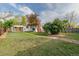 Expansive backyard showcasing lush greenery, trees, and a charming white home exterior with a brick chimney at 5115 Bryant St, Denver, CO 80221