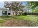 Spacious backyard with lush lawn, mature tree, walkway, and charming white exterior with orange doors at 5115 Bryant St, Denver, CO 80221