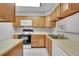 This kitchen features a white microwave and stove, light countertops, and natural wood cabinetry at 11901 E Kepner Dr, Aurora, CO 80012