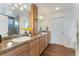 Bright bathroom featuring double vanity, wood cabinets, and a glass shower with gray tile at 18800 E 55Th Ave, Denver, CO 80249