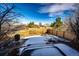 Fenced backyard with snow covering a stone patio and lush greenery under a bright blue sky at 23201 E Orchard Pl, Aurora, CO 80015
