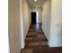 Long hallway featuring stylish wood-look flooring and neutral paint, leading to a modern front door at 914 Peach Leaf Ln, Elizabeth, CO 80107