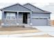 Charming home featuring stone accents, a covered entryway, and a gray garage door at 17170 E 90Th Pl, Commerce City, CO 80022