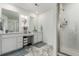 Bright bathroom with double vanity, framed mirrors, and tiled shower with glass door at 24326 E Ohio Dr, Aurora, CO 80018
