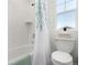 Bright bathroom featuring a bathtub with shower, a toilet, a window, and a shower curtain, providing essential functionality and comfort at 24326 E Ohio Dr, Aurora, CO 80018