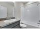 Bright bathroom with a gray vanity, a white tiled bathtub and a white toilet at 9982 Wheeling St, Commerce City, CO 80022