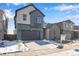 Two-story home featuring a two-car garage, gray siding and a snow-covered lawn at 9982 Wheeling St, Commerce City, CO 80022