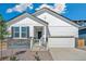 Charming white home with stone accents, a two-car garage, and a welcoming entrance under a bright blue sky at 13575 E 110Th Ln, Commerce City, CO 80022