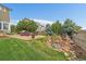 Scenic backyard with a stone waterfall, lush greenery, and cozy patio seating at 11691 Riverdale Dr, Parker, CO 80138