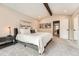 Bright bedroom with a beamed ceiling featuring neutral colors and a view into an ensuite bathroom at 6443 S Florence Way, Englewood, CO 80111