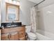 Bathroom with wood cabinets, dark countertop, tub with a shower, and a large mirror at 3048 Deer Creek Ranch Loop, Parker, CO 80138