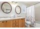 Bathroom boasts double sinks, wood cabinets, and a floral shower curtain at 4460 S Himalaya Ct, Aurora, CO 80015