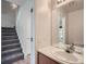 Well-lit bathroom featuring a vanity, large mirror, and adjacent staircase at 3033 W 107Th Pl # D, Westminster, CO 80031