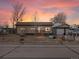 A charming home with a covered porch and quaint yard under a colorful sunset at 635 2Nd St, Bennett, CO 80102