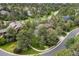 Aerial view of a wooded neighborhood with a brown two story house featuring mature trees and lush landscaping at 1122 Forest Trails Dr, Castle Pines, CO 80108