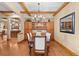 Dining room featuring hardwood floors, beamed ceiling, chandelier, and adjacent kitchen at 1122 Forest Trails Dr, Castle Pines, CO 80108