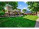 Lush green backyard featuring a covered patio, brick accents, wood fence, and mature trees for privacy at 7486 S Washington St, Centennial, CO 80122