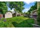 Expansive backyard featuring lush green grass, mature trees, a storage shed, and garden beds for outdoor enjoyment at 7486 S Washington St, Centennial, CO 80122