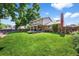 Expansive lawn featuring mature trees, a covered patio, brick accents, and a wooden fence for privacy at 7486 S Washington St, Centennial, CO 80122
