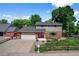 Charming two-story home featuring a well-manicured lawn, brick accents, mature trees, and a welcoming red front door at 7486 S Washington St, Centennial, CO 80122