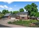 Charming two-story home featuring a well-manicured lawn, brick accents, mature trees, and a welcoming red front door at 7486 S Washington St, Centennial, CO 80122