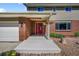 Inviting front porch with a red door, hanging flower baskets, and a well-maintained brick and siding exterior at 7486 S Washington St, Centennial, CO 80122
