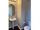 Compact powder room features a pedestal sink, round mirror, and a toilet with a minimalist design at 1251 N Burlington Dr, Castle Rock, CO 80104
