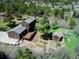 An aerial view of the home, expansive deck, several outbuildings and lush, mature landscaping at 18170 Forest View Rd, Monument, CO 80132