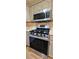 Close-up of updated gas range, stainless microwave, tile backsplash and tan-painted cabinets at 18170 Forest View Rd, Monument, CO 80132