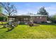 Lush backyard with a brick patio seating area, green lawn, mature trees, and inviting outdoor space at 3061 S Mabry Ct, Denver, CO 80236