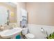 Well-lit bathroom with pedestal sink, toilet, and decorative shelving for storage at 6210 Wescroft Ave, Castle Rock, CO 80104