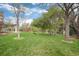Manicured green backyard with covered porch and trees on a partially cloudy day at 4800 S Franklin St, Cherry Hills Village, CO 80113