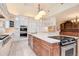 Bright kitchen with white cabinetry, stainless steel appliances, and large island with cooktop at 4800 S Franklin St, Cherry Hills Village, CO 80113