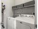 Convenient laundry room equipped with modern washer, dryer, and storage shelving at 8855 E 55Th Ave, Denver, CO 80238