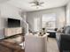 Airy living room features a gray sectional, stairs, a ceiling fan, and a large window at 8855 E 55Th Ave, Denver, CO 80238