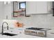Detailed shot of the kitchen with a gas range, hood, and custom tile backsplash and shelving at 1085 S Cook St, Denver, CO 80209