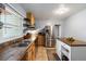 Well-lit kitchen with stainless steel appliances, an island, ample counter space, and open shelving for storage at 60 Vrain St, Denver, CO 80219