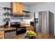 Well lit kitchen featuring stainless steel appliances, wooden cabinets, and floating wooden shelving at 60 Vrain St, Denver, CO 80219