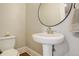 Bright powder room featuring a pedestal sink, round mirror, and classic fixtures at 404 S Grant St, Denver, CO 80209